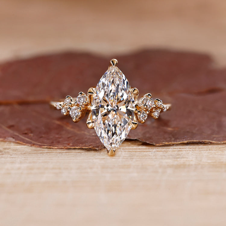Marquise cut engagement ring with round cut side stones in a diamond ring design with a cluster setting.
