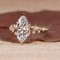 Cluster setting with marquise cut engagement ring and round cut side stones in a yellow gold engagement ring.

