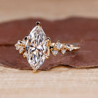Cluster setting with marquise cut engagement ring and round cut side stones in a yellow gold engagement ring.
