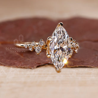 Yellow gold engagement ring with marquise cut engagement ring and round cut side stones in a cluster setting.
