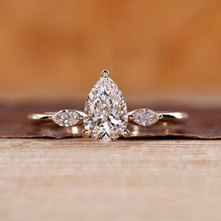 Three stone diamond ring with pear center diamond in yellow gold.
