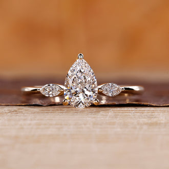 Three stone diamond ring with pear center diamond in yellow gold.
