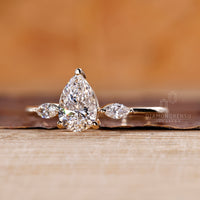 Tapered shank ring with pear center diamond and marquise side diamonds.
