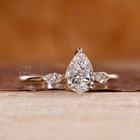 Prong setting ring holding pear center diamond and marquise side diamonds.
