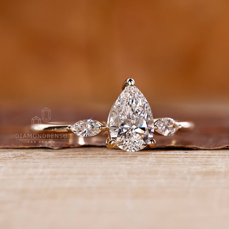 Prong setting ring holding pear center diamond and marquise side diamonds.
