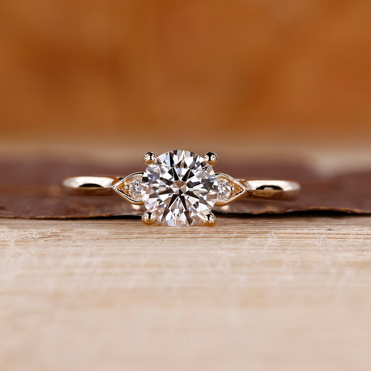 3 stone round diamond ring with cathedral setting and pear shape outline.
