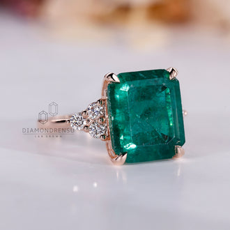 Rose gold ring with tapered shank and emerald center.
