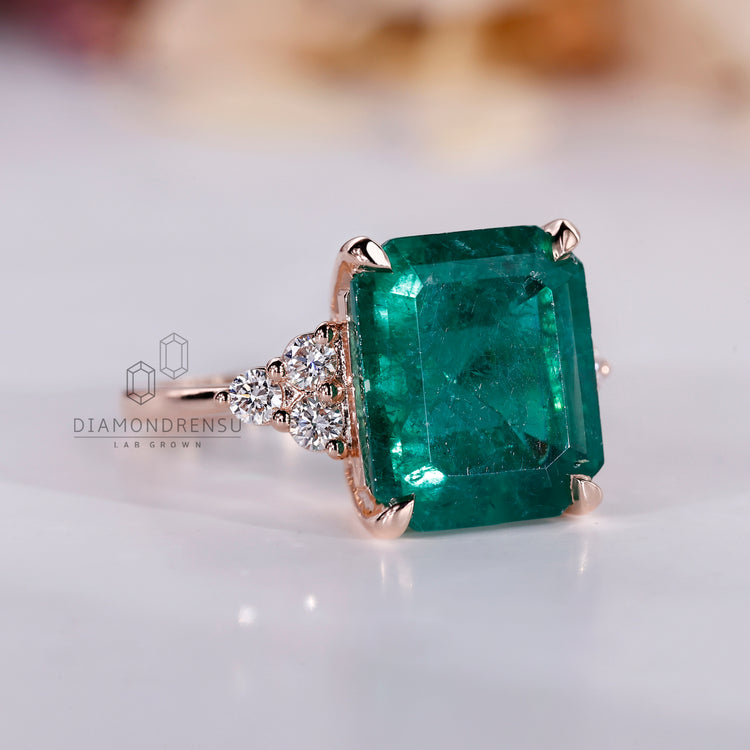 Rose gold ring with tapered shank and emerald center.
