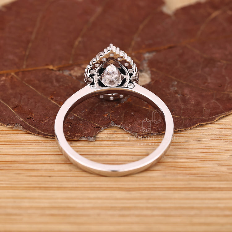 Three claw prong pear cut diamond ring with round cut halo.