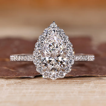 Pear cut diamond engagement ring with round cut pave band and halo setting.