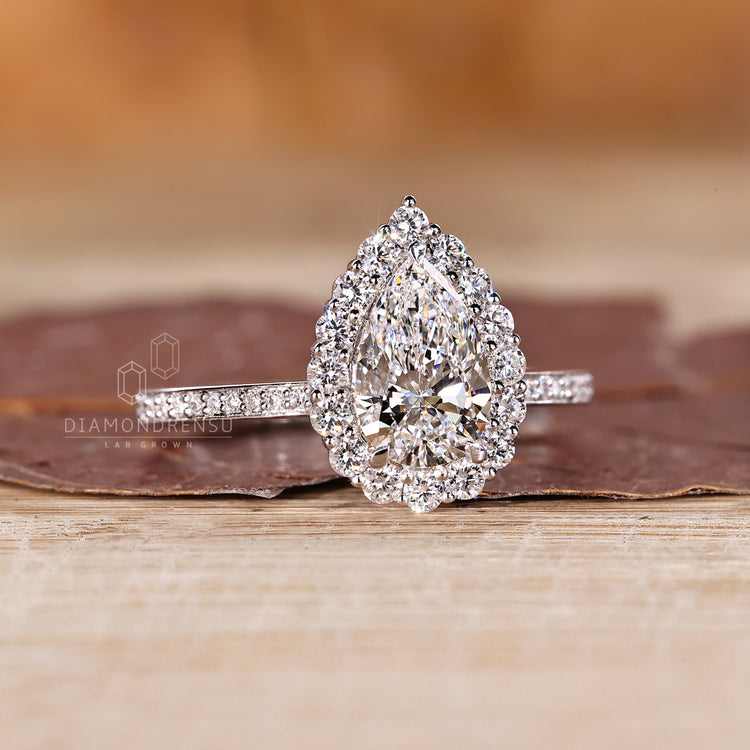 Pear cut diamond ring with round cut halo and pave accents.
