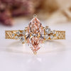 Marquise engagement ring with pink center stone and round side stones.