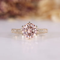 Round diamond ring with pink center stone and tapered shank.