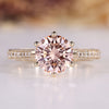 Round diamond ring with pink center stone and tapered shank.