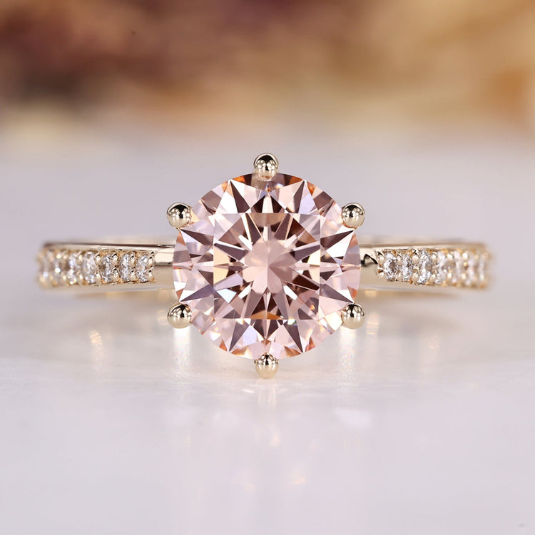 Round diamond ring with pink center stone and tapered shank.