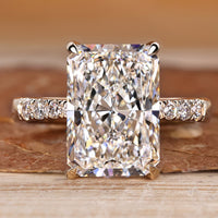 Radiant engagement ring with pave style with round stones.