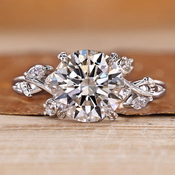 Nature inspired engagement ring with round center stone and marquise and round side stones.
