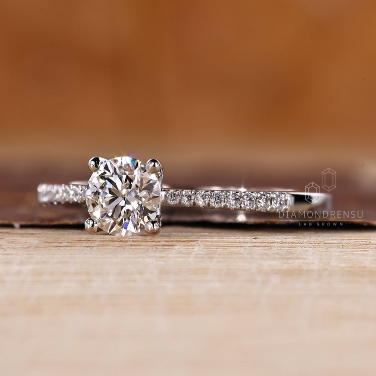 Round diamond ring with tapered shank and pave accents.