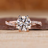 Round diamond engagement ring with twisted shank band and pave accents.