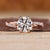 Round diamond engagement ring with twisted shank band and pave accents.