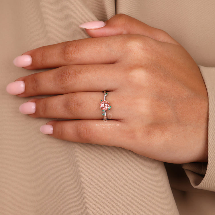 Cluster diamond ring with green emerald and peach gemstone details.