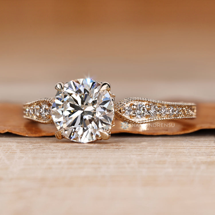 Round cut diamond ring with filigree and milgrain details.