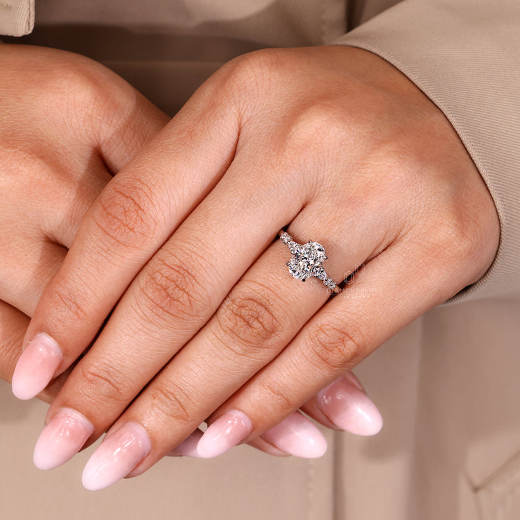 Four claw prong oval cut diamond ring with round and pear side stones.