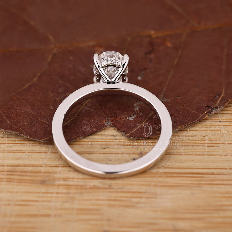 Four claw prong oval diamond ring with hidden halo accents.
