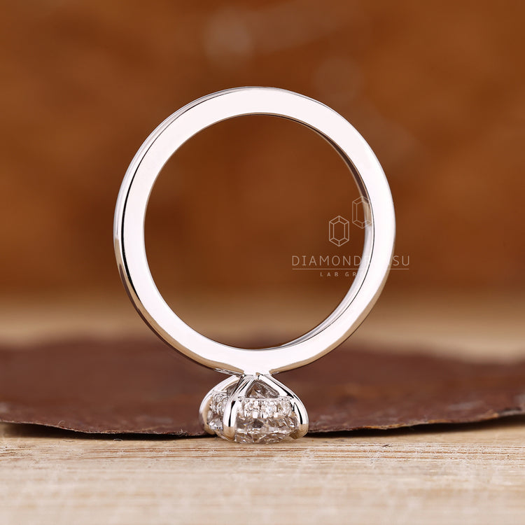 Handmade oval diamond engagement ring with four claw prong and hidden halo.
