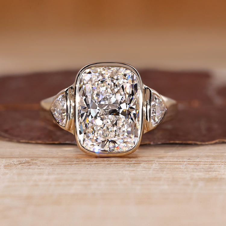 Three diamond ring with cushion cut center diamond and trillion side diamonds.