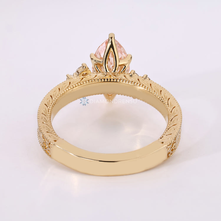 Six claw prong setting secures the pink center stone.