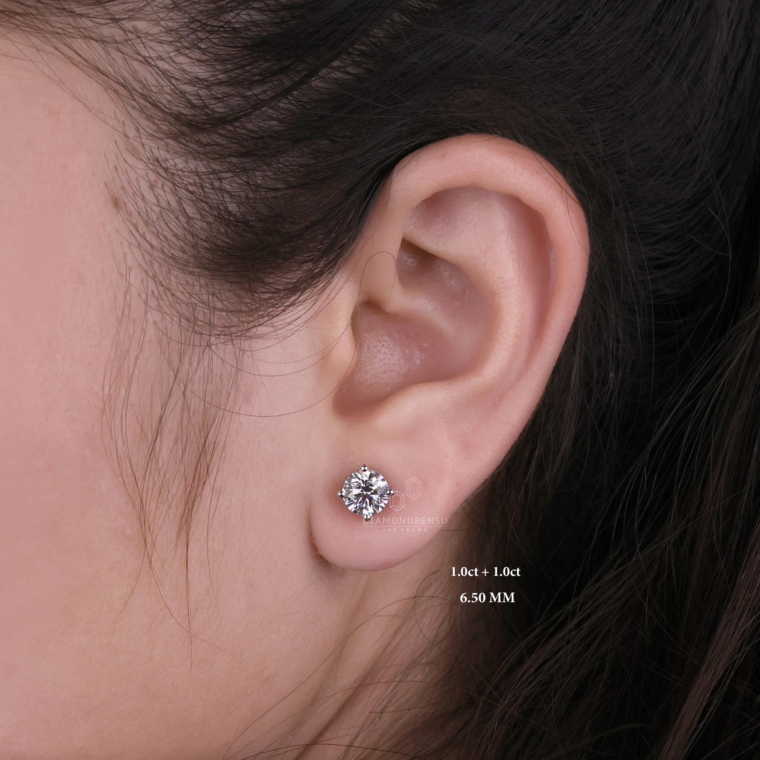 Gold stud earrings on an ear model, captured in a sunlit setting to enhance their warm glow.