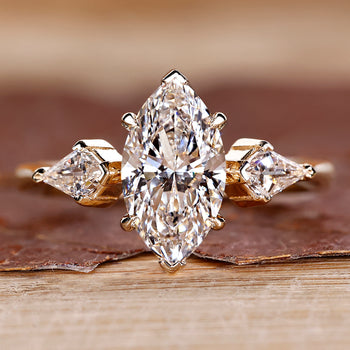 Three stone ring featuring marquise diamond and kite cut side stones.
