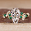Coffin cut engagement ring with green emerald and round side stones.