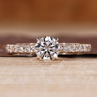Round cut engagement ring with a pave setting crafted in yellow gold.
