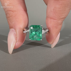 Green emerald ring featuring round diamond pave in white gold.
