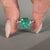 Green emerald ring featuring round diamond pave in white gold.

