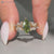 Green marquise diamond ring with a cluster setting.