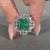 Asscher cut emerald gemstone ring in white gold.
