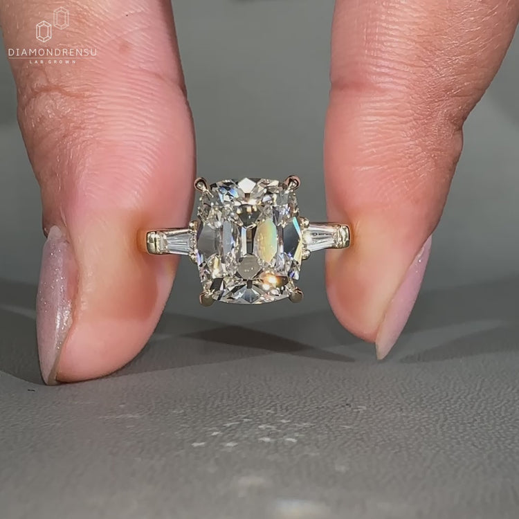 Cushion cut ring featuring a round center diamond with tapered baguette side stones for added detail.
