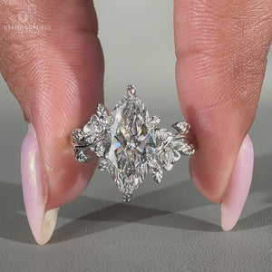 Round side stones surrounding a marquise diamond, set in a white gold band for a clean finish.
