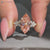 Pink center diamond marquise ring with cluster setting.