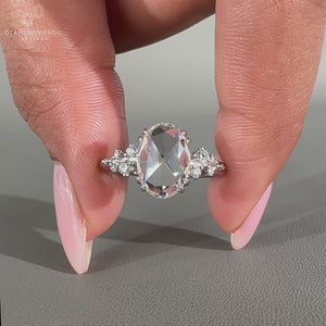 Cluster diamond ring featuring oval rose cut diamond and side stones.
