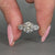 Round engagement ring with pear side stones and 4 claw prong setting.
