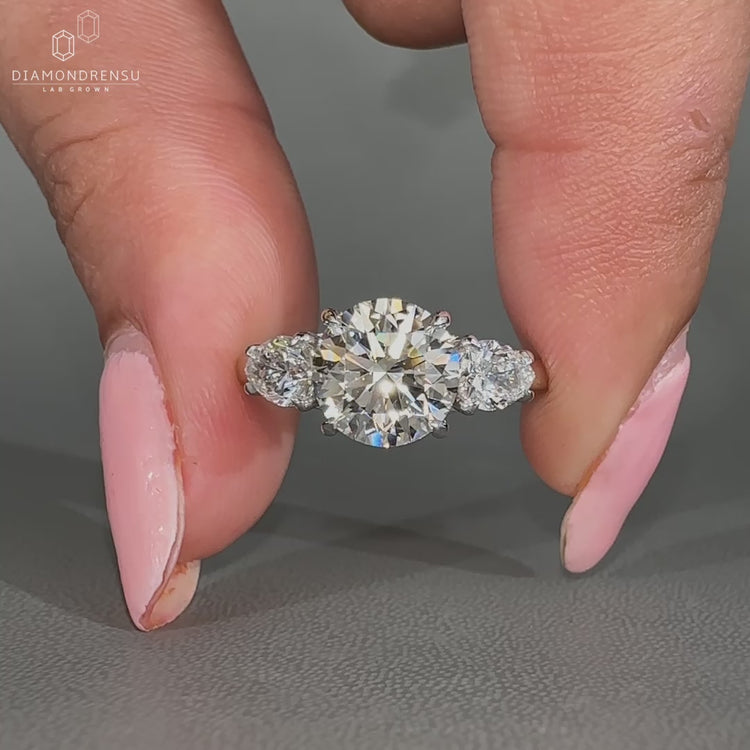 Round engagement ring with pear side stones and 4 claw prong setting.
