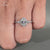 Oval engagement ring with halo and pave round diamonds.