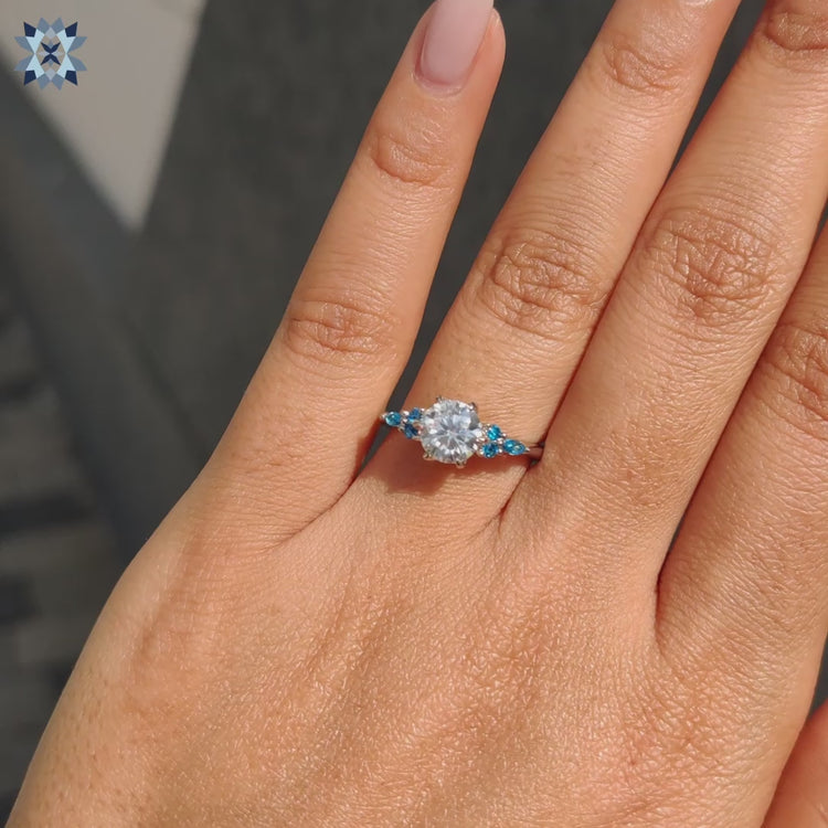 Side stone engagement ring blue round cut sidestones claw prongs.
