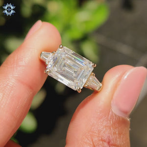 Tapered baguette engagement ring featuring side stones and an emerald cut moissanite.
