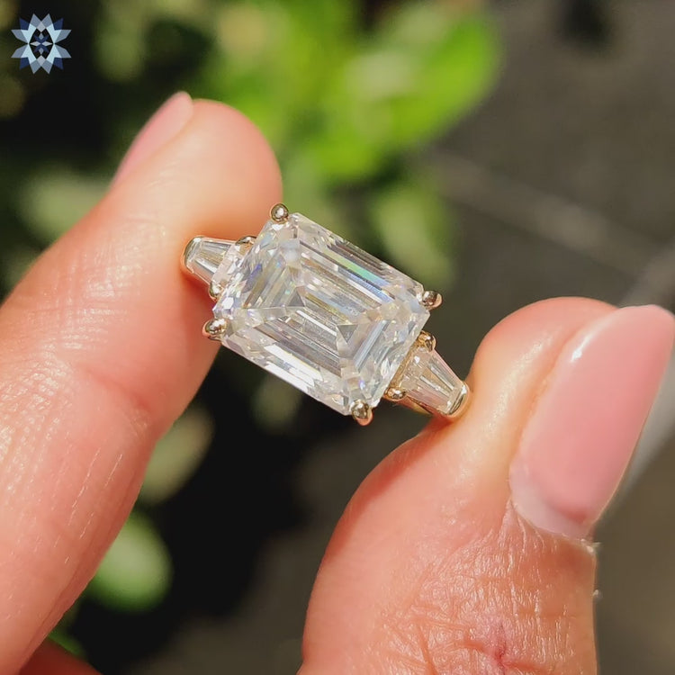 Tapered baguette engagement ring featuring side stones and an emerald cut moissanite.
