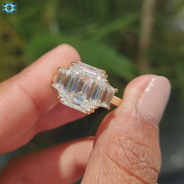 Emerald cut moissanite ring set in a modern three stone engagement design.
